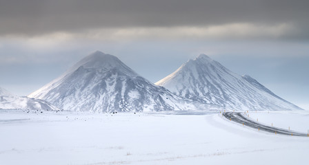 Twin snow covered sunlit volcanic peaks near Lake Myvatn, North Iceland