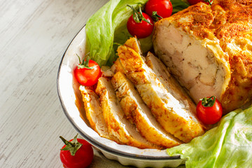 Homemade chicken ham. Oven baked chicken roll. Cold meat served with fresh cheery tomatoes and lettuce