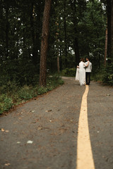 Fototapeta premium Happy stylish smiling couple walking in Tuscany, Italy on their wedding day,the couple is on the road on which the markings,wedding walk