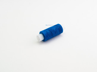 Fototapeta na wymiar a spool of blue sewing thread on a white background