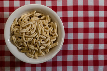Raw italian pasta in a red and white towel background top view