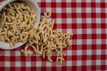 Raw italian pasta in a red and white towel background top view