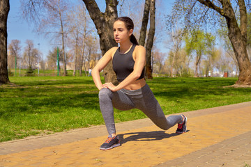 Woman runner doing stretching exercises before jogging outdoors. Beautiful smiling young athlete woman working out. Beautiful fitness girl in stylish sportswear. sport and healthy lifestyle concept.