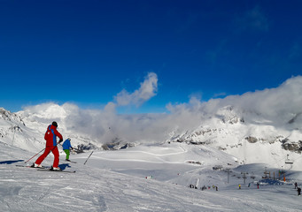 Ski slopes with skiers in the snow and blue sky