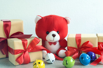 Teddy bear with Christmas or New year gifts box Red ribbon and colorful bell on wood and white background.