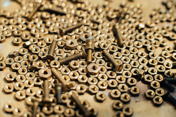 Close-up, macro. Old Soviet brass countersunk head screws with a flat head screwdriver. Texture, background of brass nuts laid out in the form of honeycombs. Gold color screws. Dirty wood screws in oi