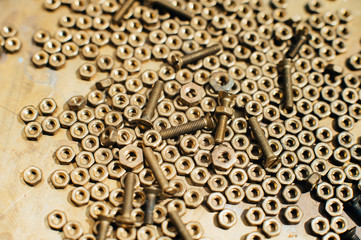Close-up, macro. Old Soviet brass countersunk head screws with a flat head screwdriver. Texture, background of brass nuts laid out in the form of honeycombs. Gold color screws. Dirty wood screws in oi