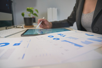 A businesswoman consults marketing statistics and analyzes the company's growth online with her tablet