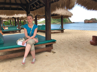 woman is sitting in a beach gazebo on an empty beach. Lombok, Indonesia, the start of the...