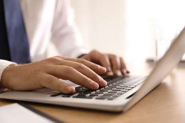 Man working with laptop in office, closeup of hands