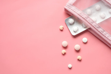 Top view of white pills and blister pack on pink 