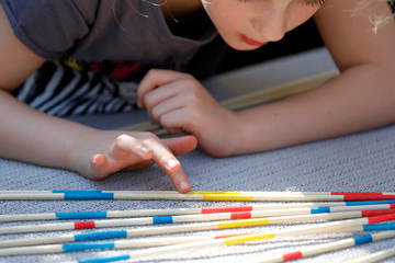 Mädchen spielt Geschicklichkeitsspiel Riesen-Mikado mit großen Holzstäben