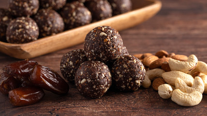 Chocolate Energy Protien Balls Made of Raw Organic Nuts and Dates on a Wooden table