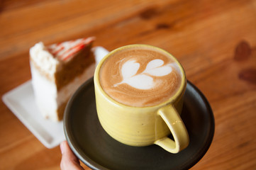 cup of coffee with a table and cake in the background, defocused background