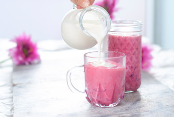 Obraz na płótnie Canvas Beautiful light fruit yogurt in the glass with white and pink colors. Berries smoothie. Milk natural organic products