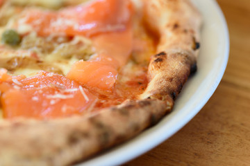 Homemade pizza with capers on a wood table