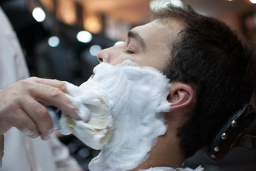 Obraz na płótnie Canvas Young and handsome man at a barbershop shaving
