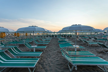Italy ,summer ,empty deck chairs are on the beach at sunset, picture without people, clear proportions, geometry