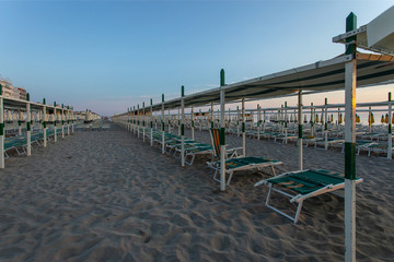 Naklejka premium Italy ,summer ,empty deck chairs are on the beach at sunset, picture without people, clear proportions, geometry
