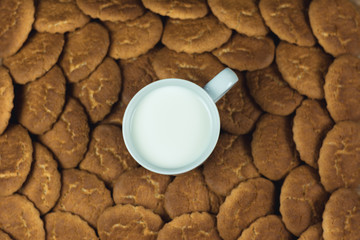 Obraz na płótnie Canvas Taza llena de leche blanca en un montón de galletas doradas