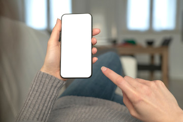 Template mockup smartphone with white screen. A young woman use the smartphone for socialize and shopping online on the sofa at home.