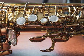 Closeup of saxophone keys on a wood surface.