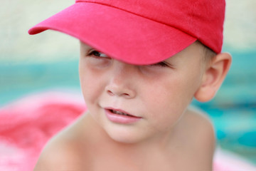 Cute boy in red cap outdoor portrait, close-up, sun on the sea beach