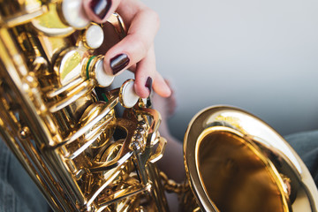 Obraz na płótnie Canvas Saxophone girl player hands. Saxophonist playing jazz music. Alto sax musical instrument closeup. Painted nails.