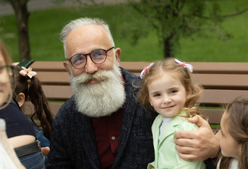 Bearded senior man in park playing with children. Grandfather having fun with granddaughter.