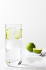 Gin tonic glass with ice cubes and lime slices. Gin tonic preparation