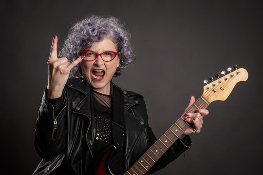 Close Up Portrait Of Beautiful Old Woman Playing Electric Guitar On A Gray Background