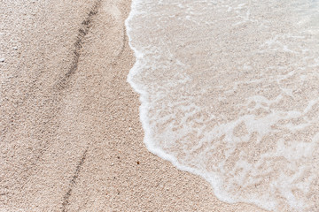 Close up of foamy sea and sandy beach.  Beach background with copy space. Summer background. Exotic vacation. Winter beach holidays. Family vacation. Honeymoon destination.
