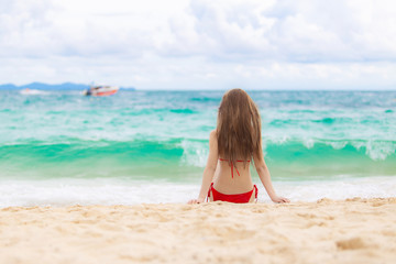 Young beautiful sexy woman wearing pink bikini and relaxing on the white sandy beach near the waves of blue on tropical beach background near ocean / Summer concept.