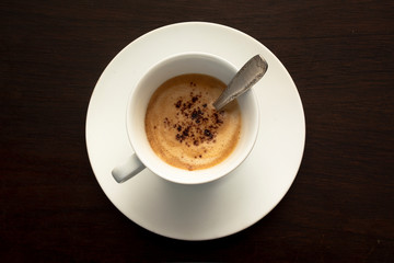 top view of white cup of coffee on a dark black background.