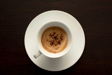 top view of white cup of coffee on a dark black background.