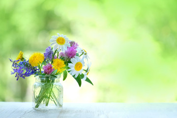 meadow flowers - chamomile, dandelion, clover on white table. beautiful floral composition. summer blossom season