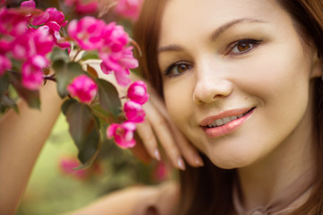 portrait of a beautiful young woman with make-up near a tree with flowers