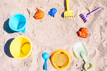 Selection of beach toys on white sandy beach. Top view of colourful hildren's toys to play in sand on family summer vacation. Background with empty space for text. Selective focus