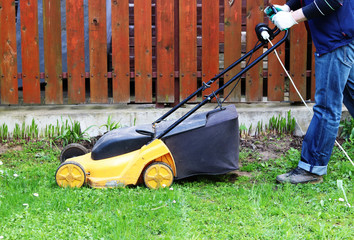 man mows grass with a lawn mower