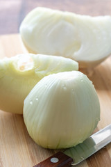Peeled onions on a wooden board with a knife, food