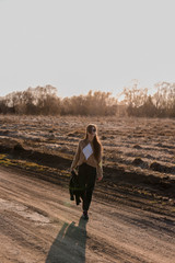 Young girl walking on a dirt road in nature. A young woman in a leather jacket in nature