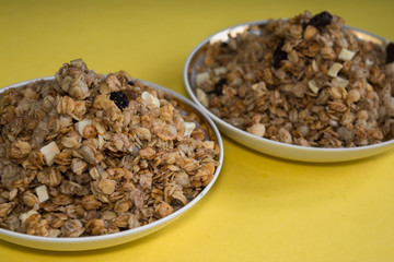 muesli fried cereals in a plate gold dried fruits raisins on a yellow background place for text