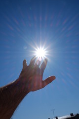 hand reaching the sun and blue sky background 