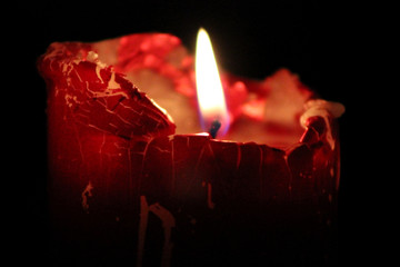 Gran vela roja en fondo negro con una gran llama de fuego en el centro de la misma