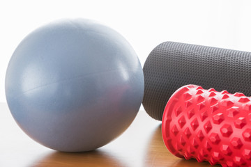 A blue ball and a grey pilates roller and a red fascial massage roller,