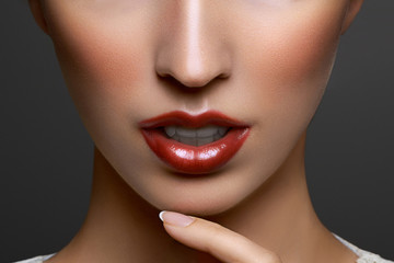 Close-up portrait of beautiful young woman lips with bright red lipstick