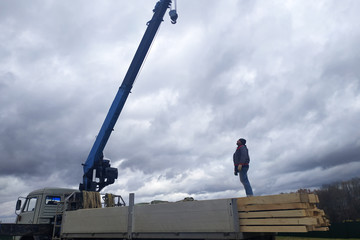 The crane lowers the roof construction boards.