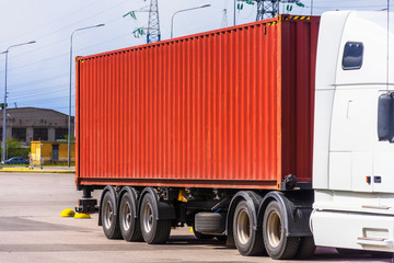 Truck trailer with a brown metal cargo container parked.