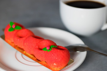 Red mousse cake and a white cup of espresso on a gray background.
