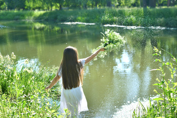 Girl in beautiful wreath on summer meadow near the river. Feast of Ivan Kupala.Midsummer. Earth...